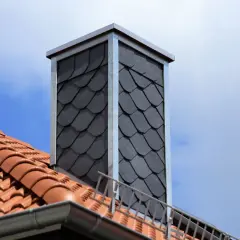 Moderner Schornstein mit Schieferplatten verkleidet. Beachten Sie die **Schornstein verkleiden Vorschriften** für eine sichere und ästhetische Lösung.