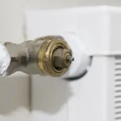 Nahaufnahme eines Heizungsventils, bei dem der Stift klemmt. Das Messingteil ist sichtbar, daneben ein weißer Heizkörper.