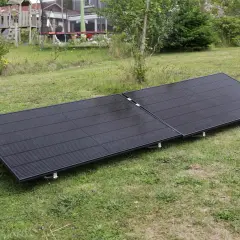 Zwei schwarze Solarmodule liegen auf einer grünen Wiese. Sie sind für ein Balkonkraftwerk gedacht und fragen sich, wie viel Watt sie haben dürfen.