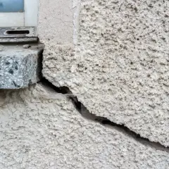 Tiefe setzrisse altbau, die sich vom Fensterrahmen aus durch die raue Fassade ziehen.