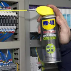 Hand sprüht mit WD-40 Kontaktspray auf elektrische Klemmen, um korrodierte Kontakte zu reinigen und die Funktion sicherzustellen.