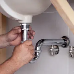 Hände montieren ein neues Siphon unter dem Waschbecken. Der alte Siphon muss ausgetauscht werden, um Lecks zu vermeiden.