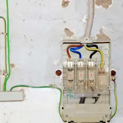 Sicherungskasten mit drei Sicherungen und farbigen Kabeln. Grüne und gelbe Kabel zeigen die Erdung und den Potentialausgleich gemäß Vorschriften.