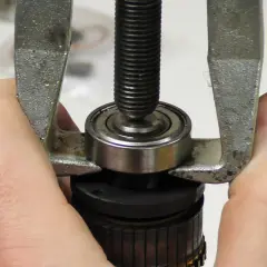 Hände führen einen Abzieher, um ein Kugellager zu montieren.