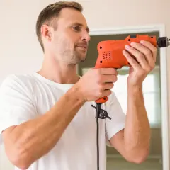 Mann bohrt vorsichtig in die Wand, um eine Stromleitung zu finden.