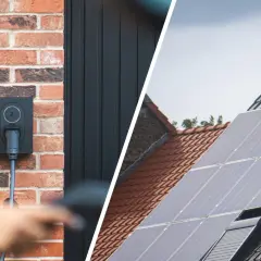 Wallbox an Ziegelwand, bereit für das photovoltaik e auto laden. Daneben Solarmodule auf einem Dach.