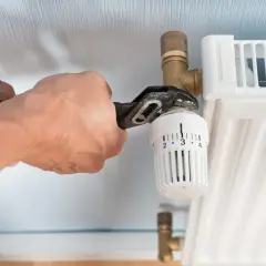 Hände wechseln Heizkörperthermostat mit Zange.