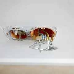 Einbau einer Doppelsteckdose: Freiliegende Kabel und orangefarbene Unterputzdose in einer Decke.