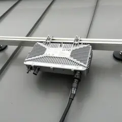 Ein Mikrowechselrichter wird auf einer Schiene montiert, die auf einem Metalldach befestigt ist. Die Montage ist einfach und sicher.
