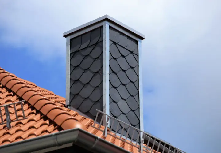 Moderner Schornstein mit Schieferplatten verkleidet. Beachten Sie die **Schornstein verkleiden Vorschriften** für eine sichere und ästhetische Lösung.
