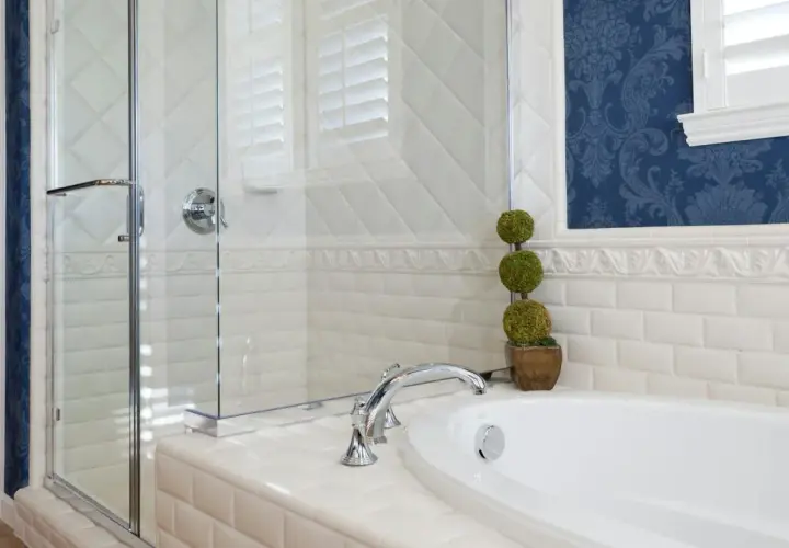 Elegantes Badezimmer mit Duschkabine, Wanne und blau gemusterter Tapete. Die weißen Fliesen und die Tapete ergeben ein stilvolles Ambiente.