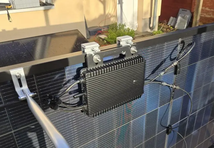 Schwarzer Wechselrichter mit Kühlrippen, montiert an Solarmodulen. Ein 800W Wechselrichter erlaubt die Umwandlung von Solarstrom.
