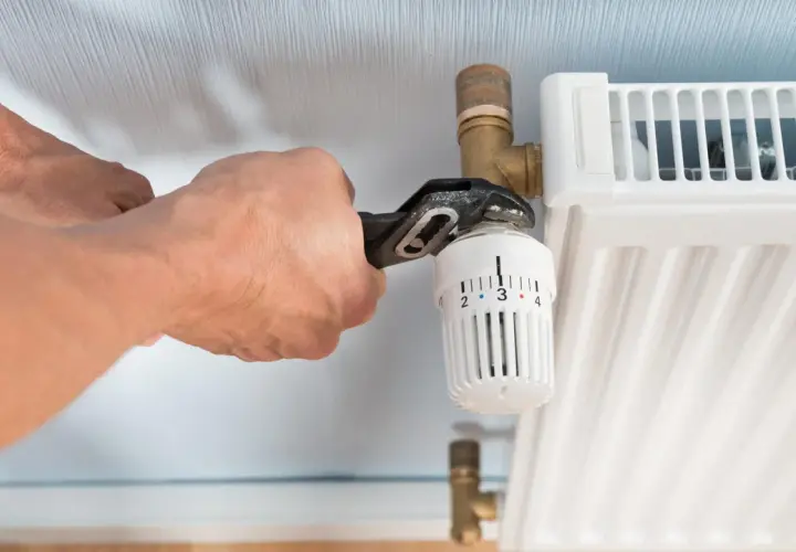 Hände wechseln Heizkörperthermostat mit Zange.