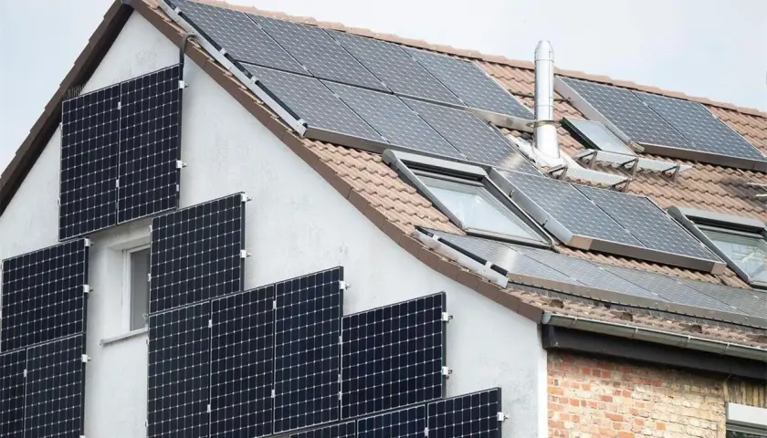 Solaranlage am Haus: Viele Module auf Dach und Fassade. Denken Sie daran, Ihre PV-Anlage beim Finanzamt anzumelden.