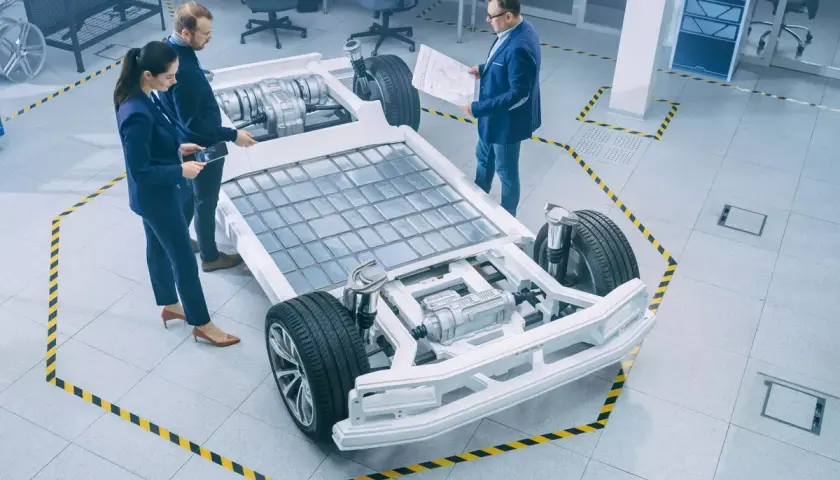 Ingenieure diskutieren über die e-auto batterie als pv speicher, die in einem modernen Labor auf einem Chassis montiert ist.