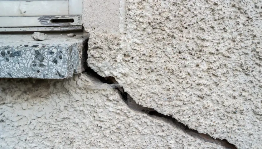 Tiefe setzrisse altbau, die sich vom Fensterrahmen aus durch die raue Fassade ziehen.