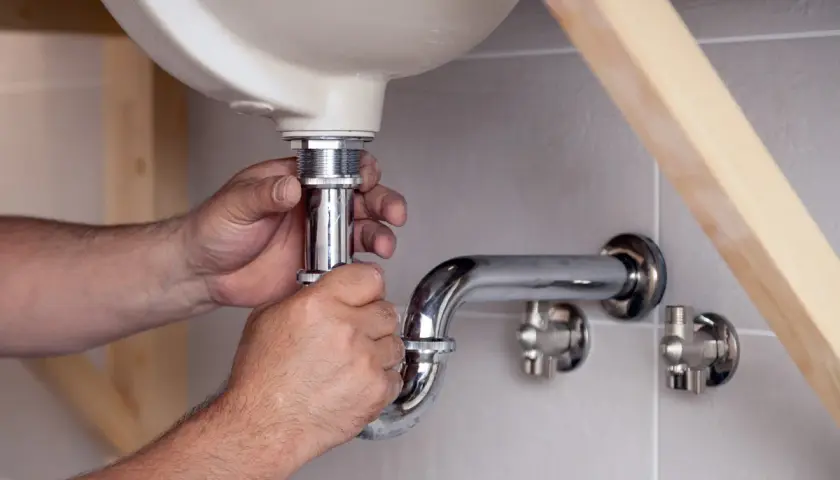 Hände montieren ein neues Siphon unter dem Waschbecken. Der alte Siphon muss ausgetauscht werden, um Lecks zu vermeiden.