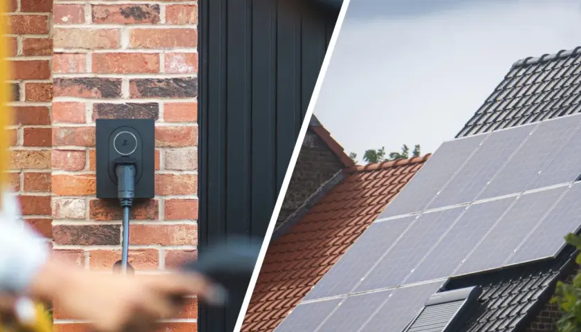 Wallbox an Ziegelwand, bereit für das photovoltaik e auto laden. Daneben Solarmodule auf einem Dach.