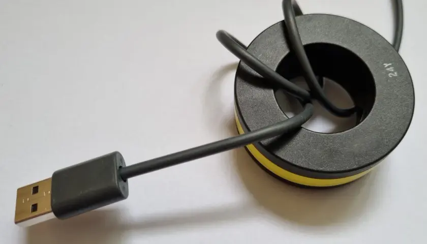 Ein USB-Kabel mit einem Ferritkern, der zur Entstörung an Kabeln angebracht wird.