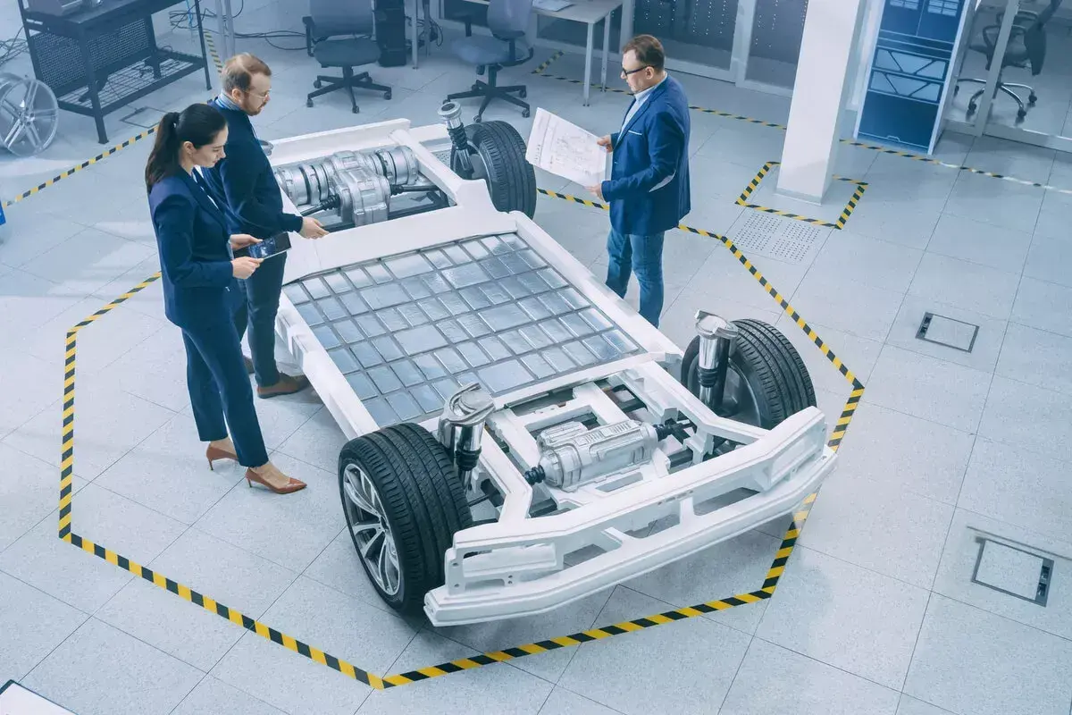 Ingenieure diskutieren über die e-auto batterie als pv speicher, die in einem modernen Labor auf einem Chassis montiert ist.