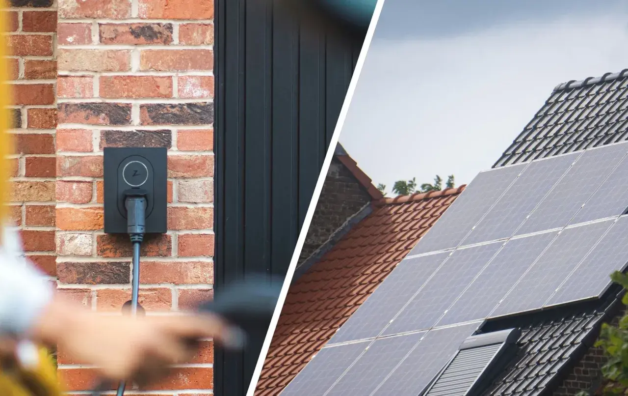 Wallbox an Ziegelwand, bereit für das photovoltaik e auto laden. Daneben Solarmodule auf einem Dach.