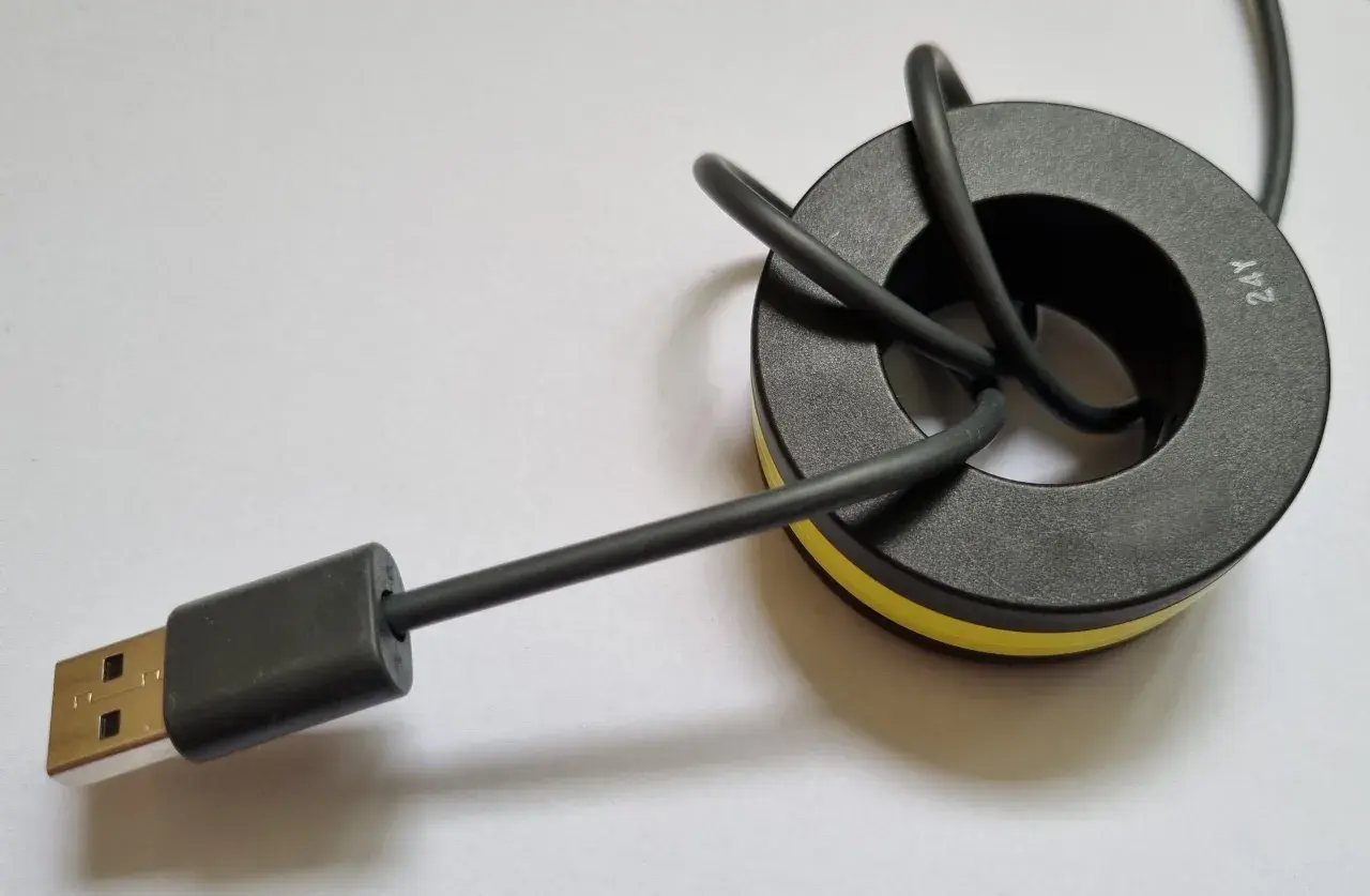 Ein USB-Kabel mit einem Ferritkern, der zur Entstörung an Kabeln angebracht wird.