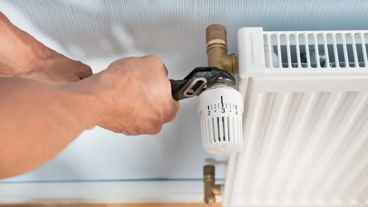 Hände wechseln Heizkörperthermostat mit Zange.