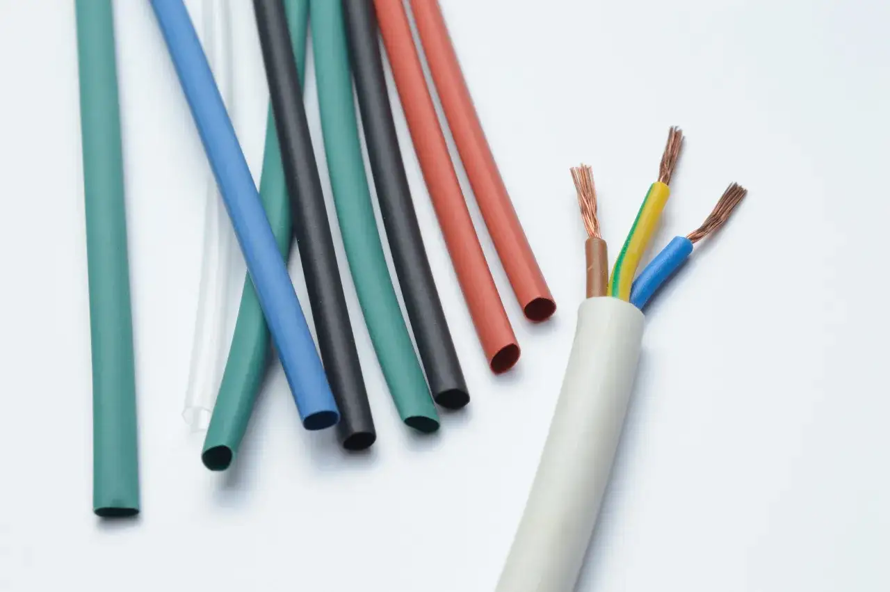 Bunte Schläuche, bereit für den Einsatz als temperatur schrumpfschlauch, liegen neben einem Kabel mit freiliegenden Adern.