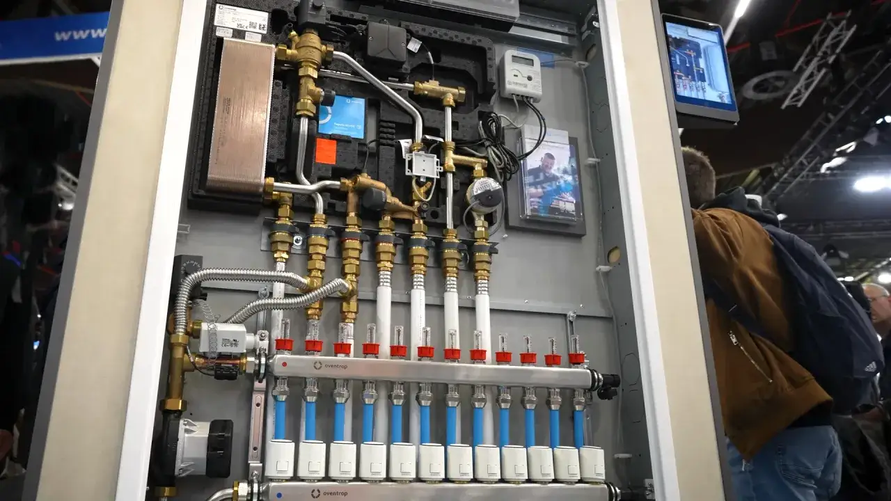 Moderne Heizungsanlage mit vielen Rohren und Ventilen. Ein Mann betrachtet die Technik, die an die Gasetagenheizung Austauschpflicht erinnert.
