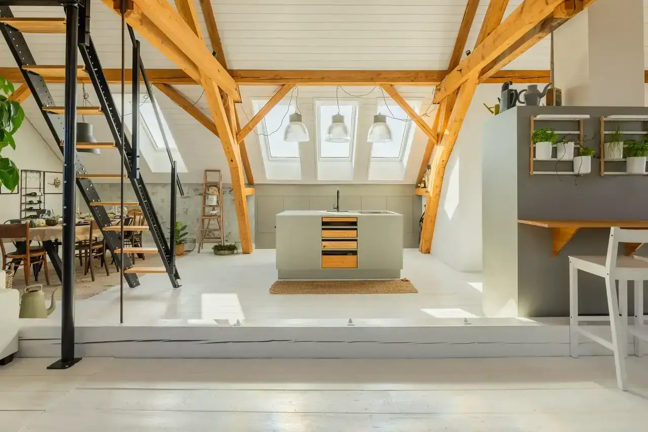 Stilvolles Loft mit freigelegten Holzbalken. Die Küche mit Insel ist das Herzstück. Die richtige Altbau sanieren Reihenfolge macht aus diesem Dachboden ein Traumhaus.