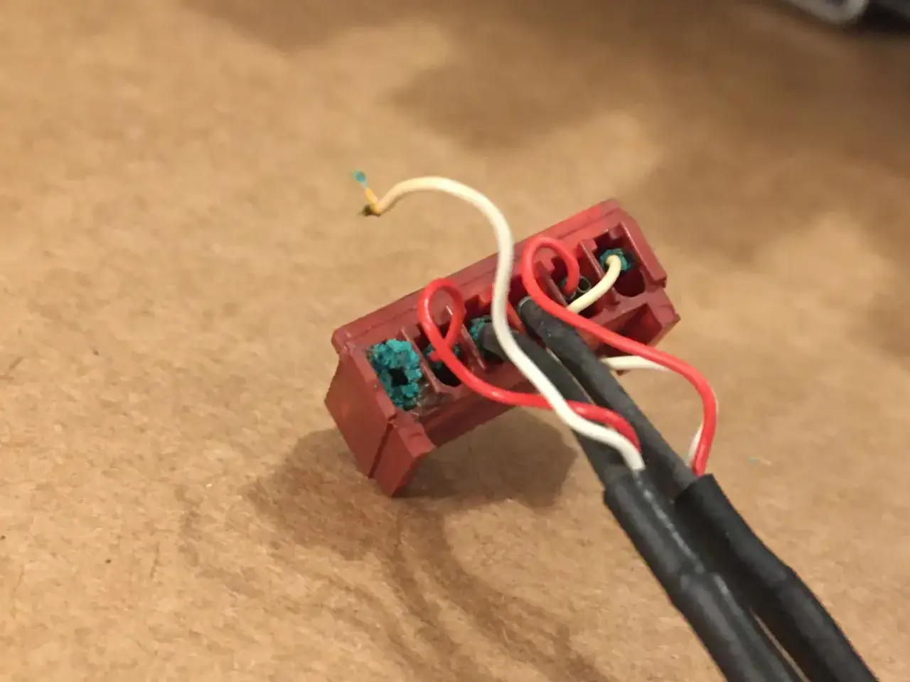 Roter Stecker mit wei&szlig;en und roten Kabeln, die korrodierte Kontakte reinigen.